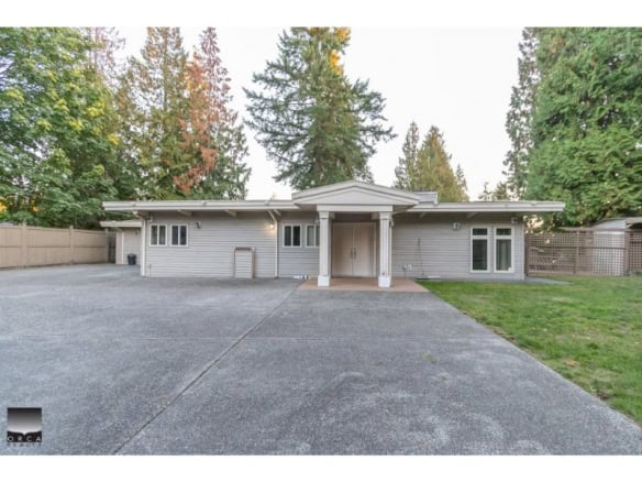 Spacious single-family home with a large driveway, surrounded by tall trees, ideal for families and outdoor enthusiasts seeking real estate opportunities in a tranquil neighbourhood.