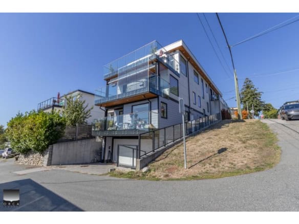 Contemporary multi-story residential building with glass balconies on a hillside in Victoria, BC, showcasing modern architecture and urban living.
