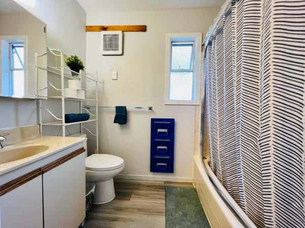 Bright bathroom with white walls, striped shower curtain, window, and modern fixtures ideal for Vancouver or BC homes.