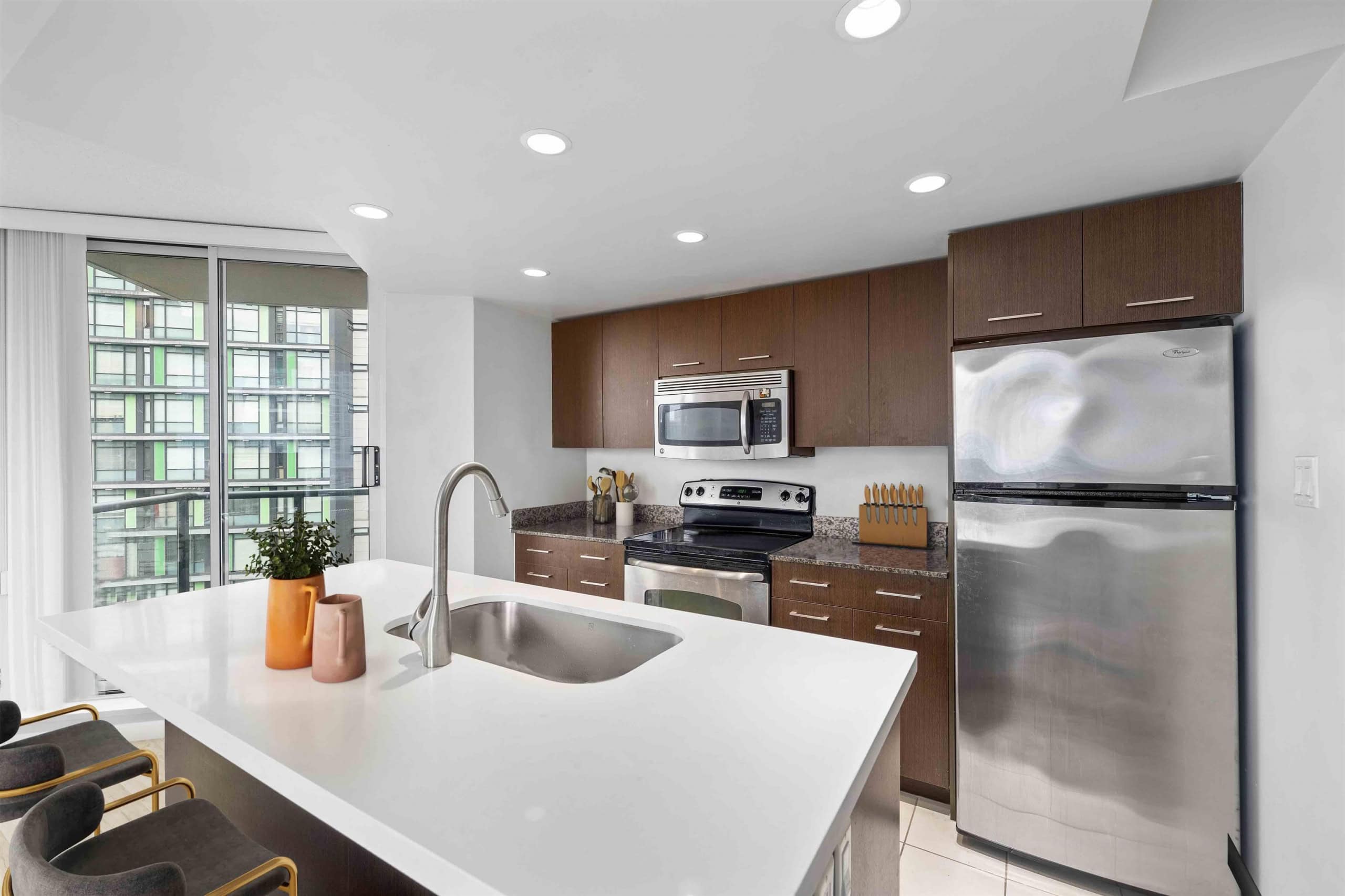 06 Modern kitchen with stainless steel appliances, granite countertops, and dark wood cabinets at Orca Realty. Perfect for Vancouver condo living and real estate investment in BC.