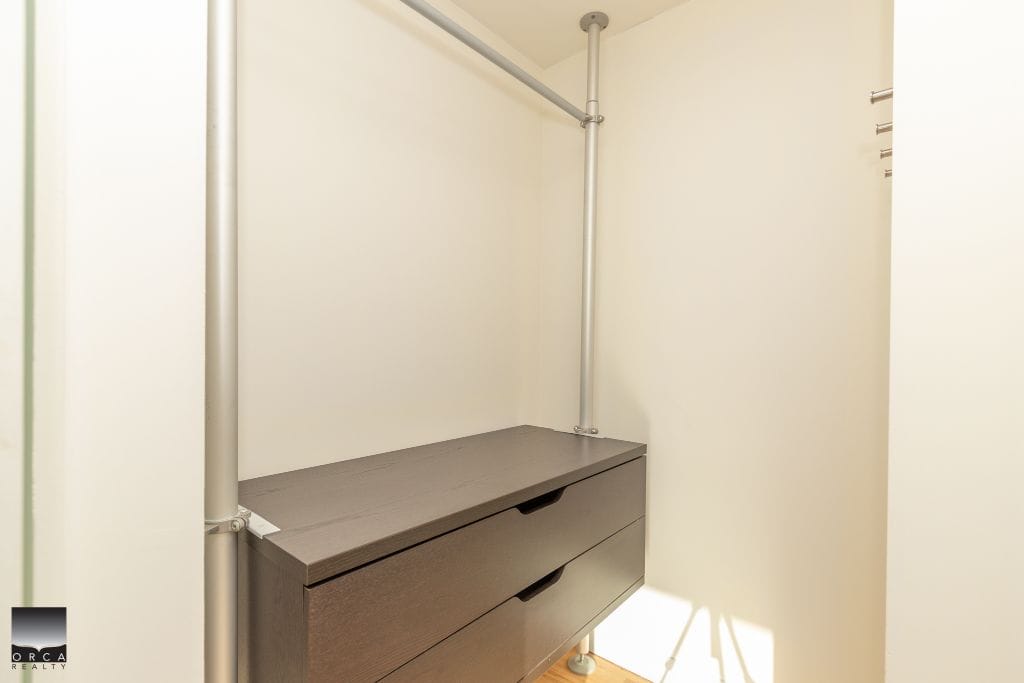 Spacious walk-in closet with modern grey drawers and hanging rods, ideal for organizing clothing and accessories in a Toronto home. Perfect for maximizing space and storage efficiency.