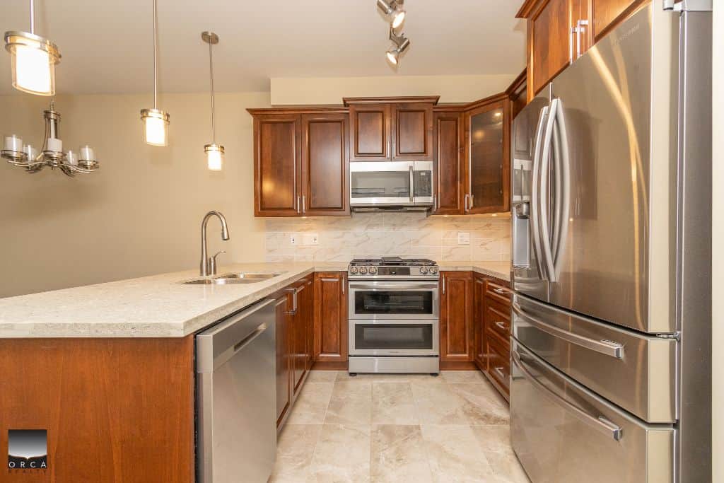 Stainless steel refrigerator and modern kitchen cabinetry in a contemporary home kitchen by Orca Realty Inc.