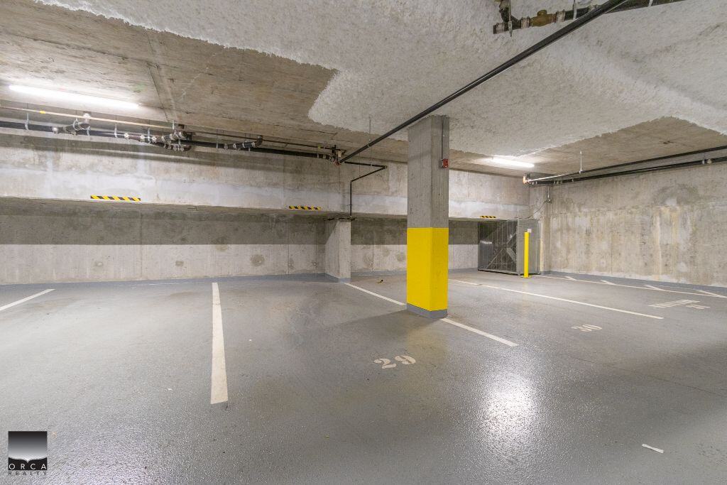 Spacious underground parking garage with numbered parking spaces, concrete walls and ceiling, bright lighting, and secure access, perfect for residential or commercial property owners.