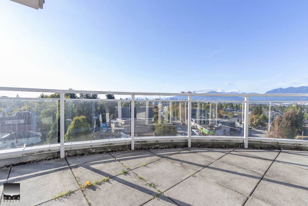 Stunning city view from a spacious balcony with glass railing, overlooking Vancouver’s skyline and mountains, ideal for real estate appreciation and outdoor living in BC.