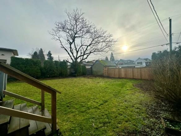 Bright backyard with lush green lawn, mature tree, wooden fence, and outdoor space, ideal for family living or gardening in Vancouver, BC. Perfectly captured for real estate marketing.