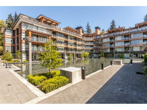 Modern multi-family residential building with scenic water feature in the courtyard, showcasing Orca Realty Inc.'s prime property listings in BC.