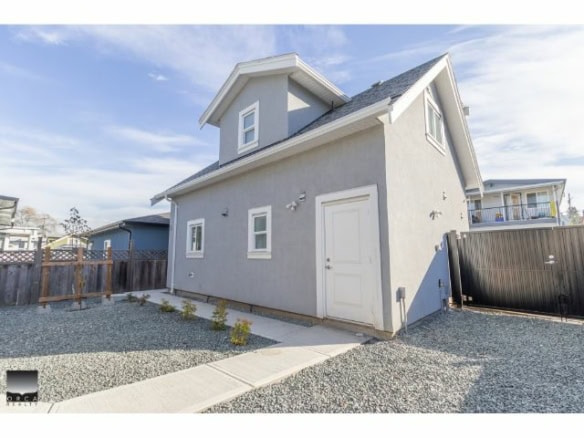 Modern grey residential house with small front yard, gravel landscaping, and white door, situated in a suburban neighbourhood in Vancouver, British Columbia.