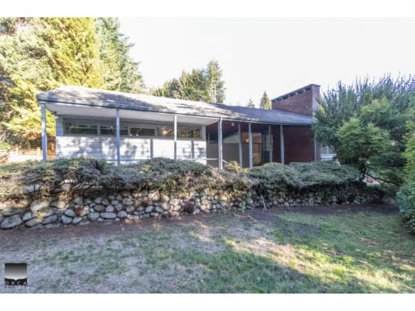 Charming mid-century modern house with large windows, surrounded by lush greenery and landscaped garden, available through Orca Realty Inc. in Vancouver, BC.