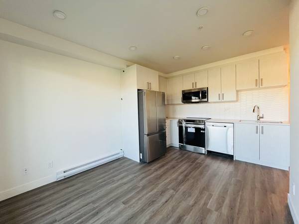Modern kitchen with stainless steel appliances, white cabinetry, and hardwood flooring, ideal for Vancouver real estate listings.