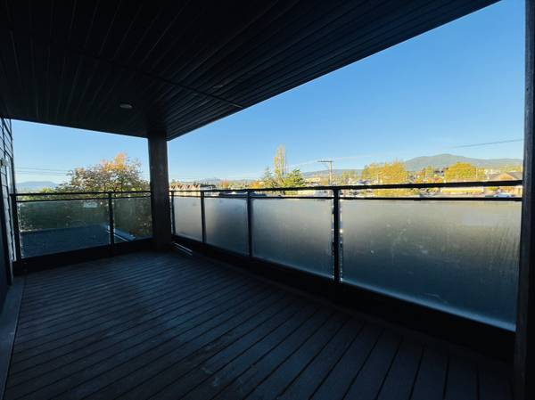 Accessible balcony with glass railing offering scenic views of trees and distant mountains, ideal for relaxed outdoor living.