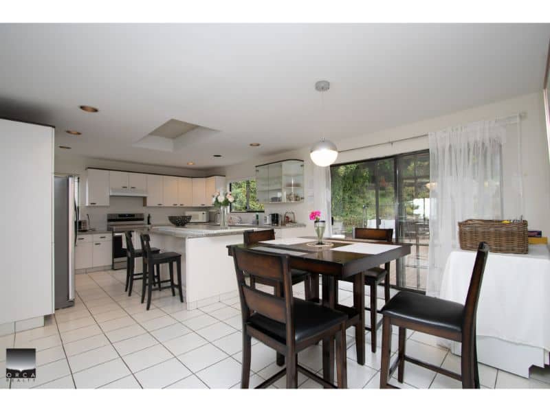 Spacious modern kitchen and dining area in a contemporary home, featuring white cabinetry, stainless steel appliances, and ample natural light through large windows. Perfect for family living and entertaining.