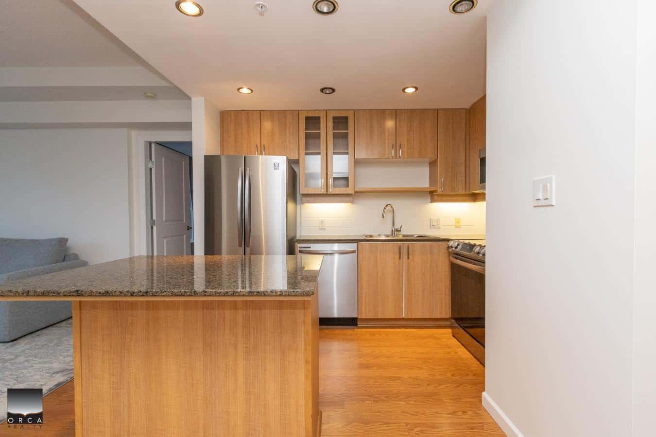 Modern kitchen with wooden cabinets, stainless steel appliances, granite countertops, and ample lighting, ideal for Vancouver Island real estate listings.