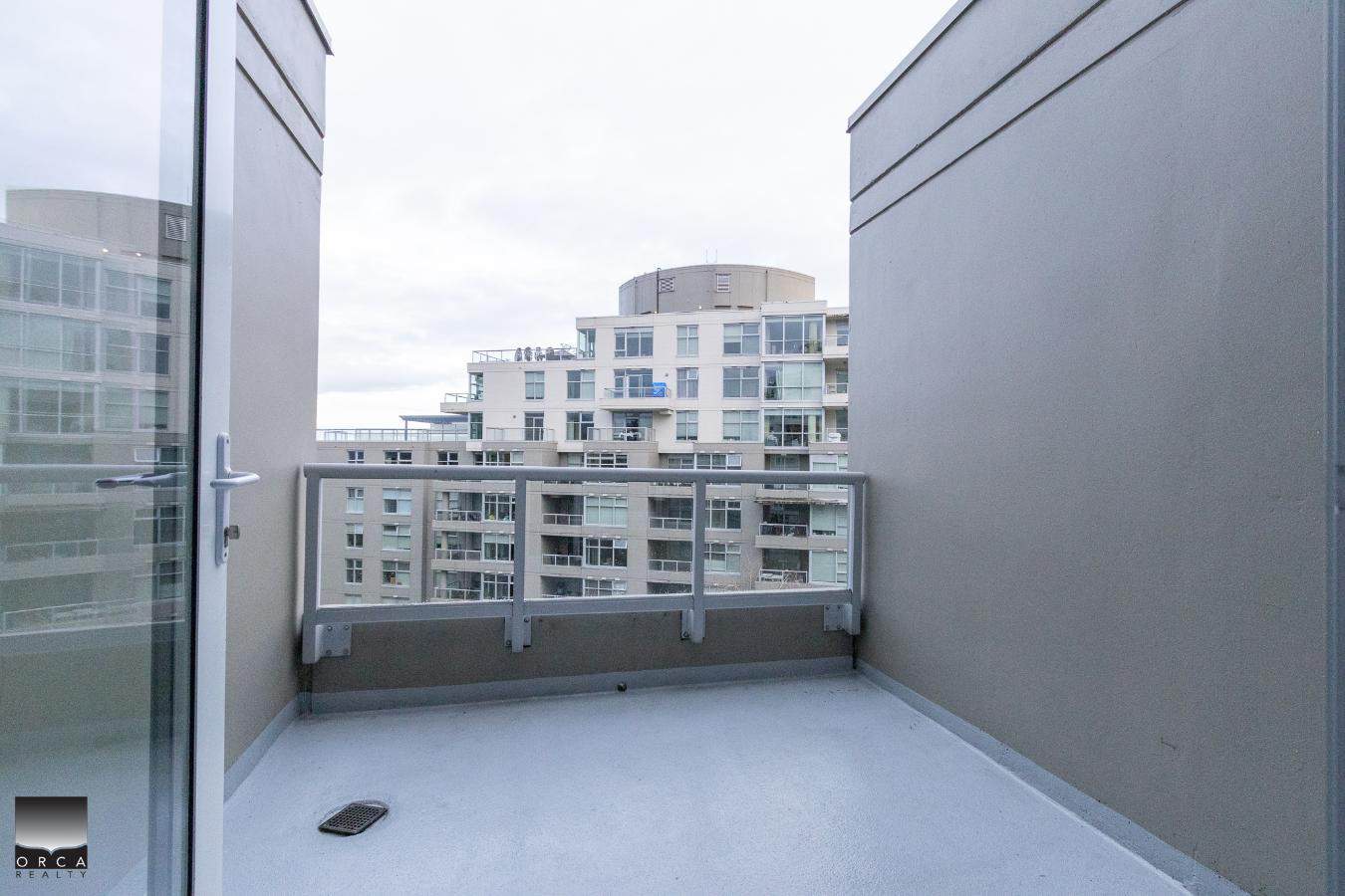 Modern balcony view from a Vancouver apartment, showcasing a sleek, open outdoor space with urban high-rise buildings in the background, perfect for city living and real estate opportunities.