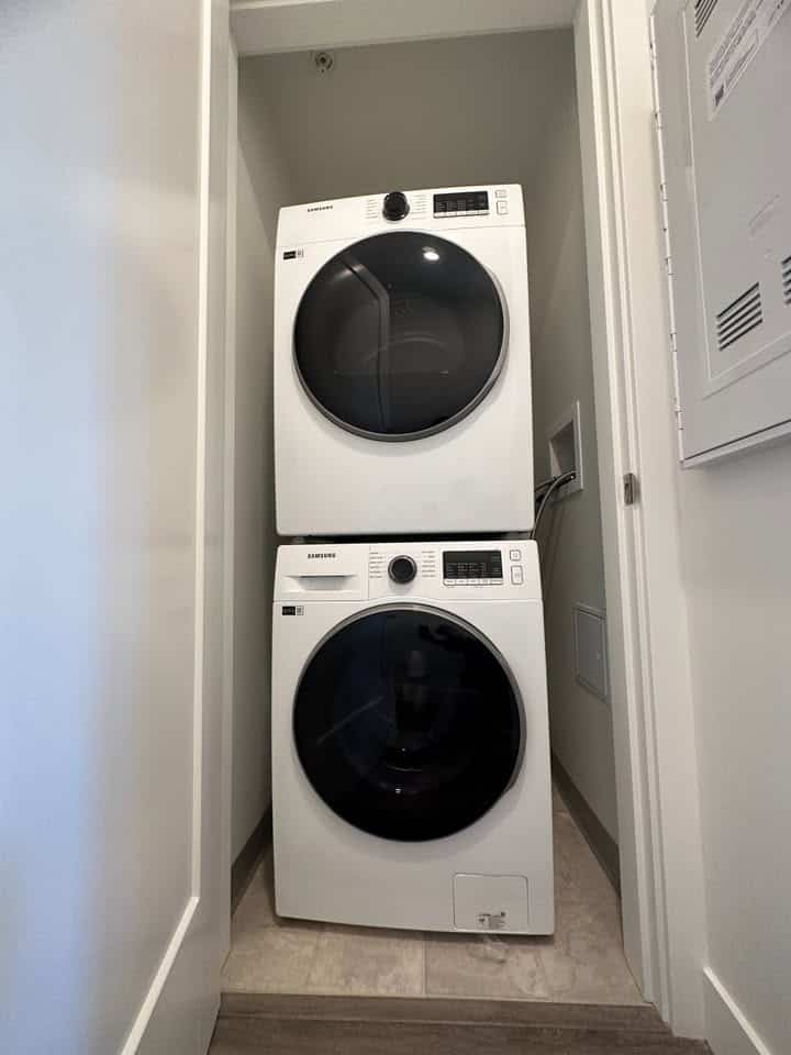 Samsung front load washer and dryer set in a compact laundry nook, ideal for Vancouver residential homes. Energy-efficient appliances perfect for modern laundry needs, provided by Orca Realty Inc.