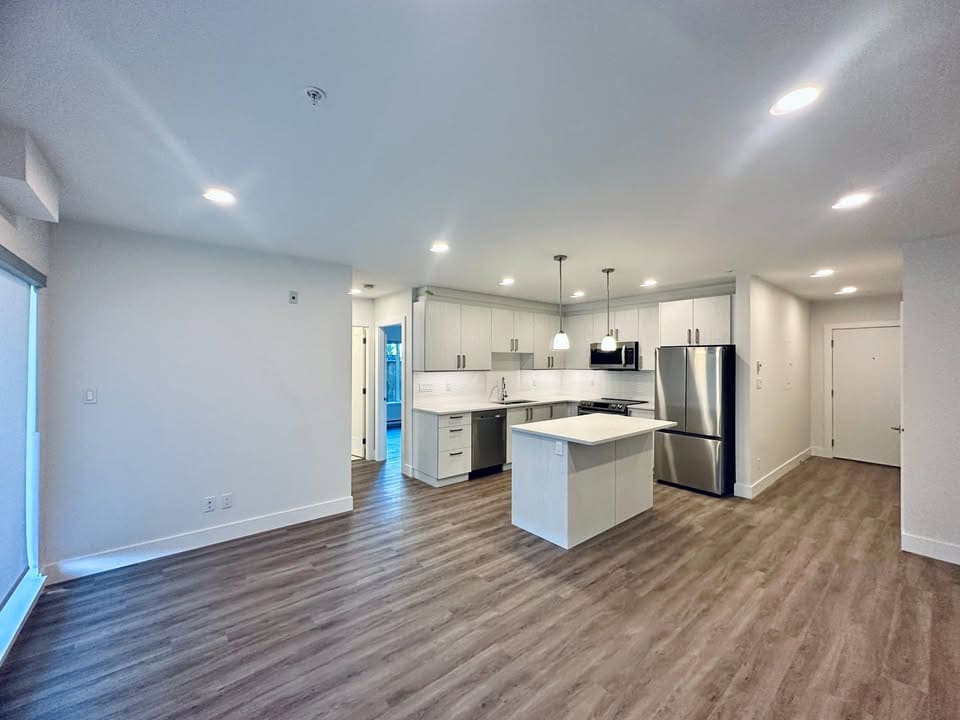 Bright modern open-concept kitchen with white cabinetry, stainless steel appliances, and a central island in a contemporary home. Perfect for family living and entertaining in Vancouver.