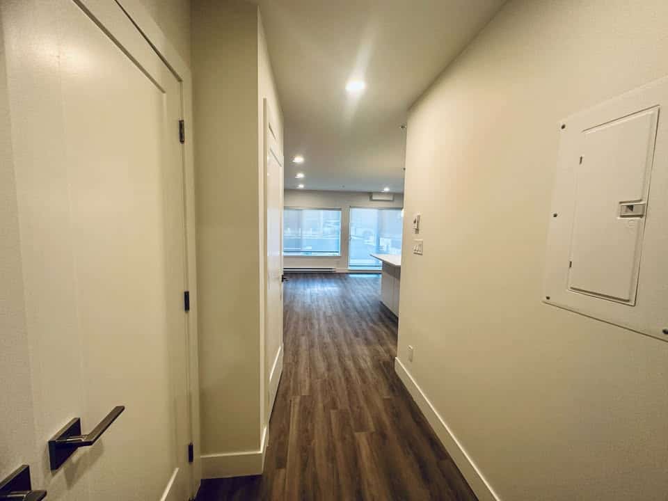 Modern apartment hallway with wood flooring and natural light, ideal for Vancouver real estate, featuring updated finishes and a spacious layout.
