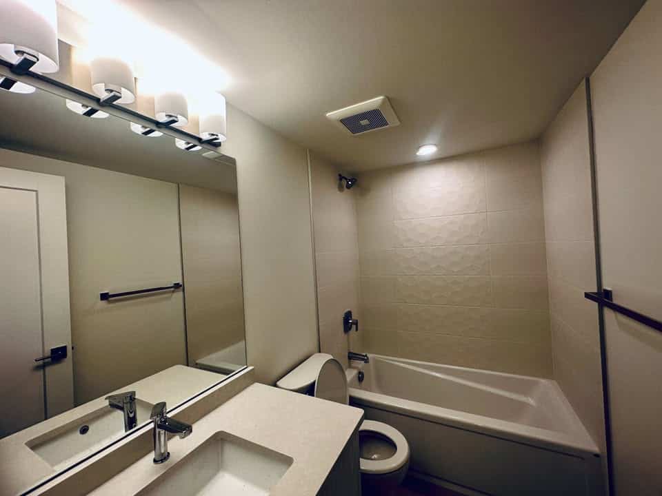 Modern bathroom with neutral tones and contemporary fixtures, perfect for Vancouver homebuyers. Featuring a bathtub, sleek vanity, and ample lighting, ideal for showcasing property listings in real estate marketing.