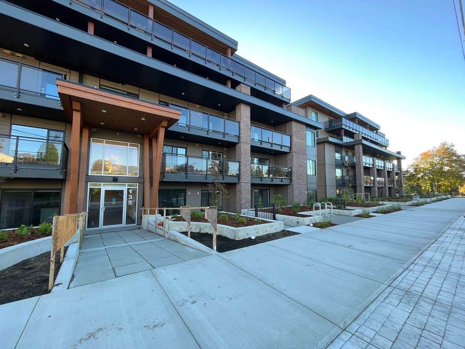 Modern multi-family residential building with balconies and landscaped walkways in Vancouver, BC.