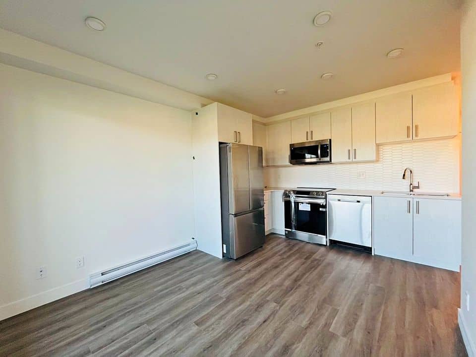 Modern Vancouver kitchen with stainless steel appliances and white cabinetry for sale or rent through Orca Realty Inc.