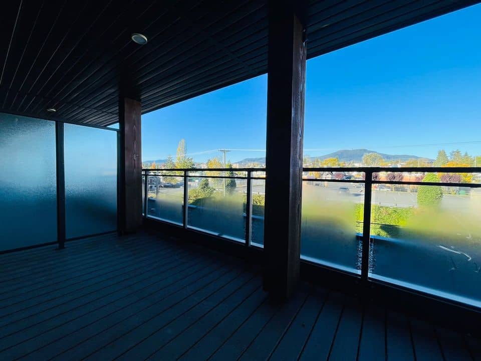 Spacious balcony with glass railing overlooking scenic neighbourhood and distant mountains in a modern home in Vancouver.