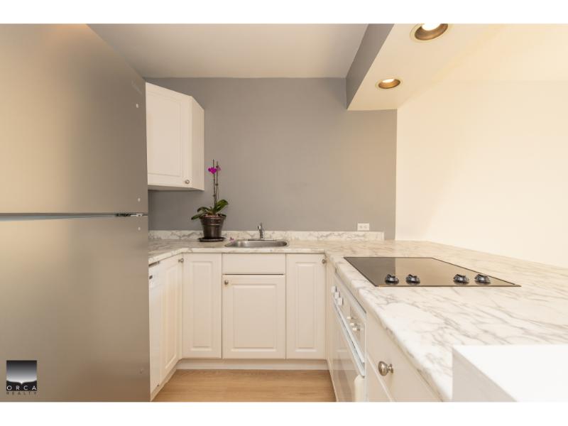 Modern white kitchen with marble countertops, stainless steel appliances, and ample cabinet space - ideal for Vancouver Island real estate listings.