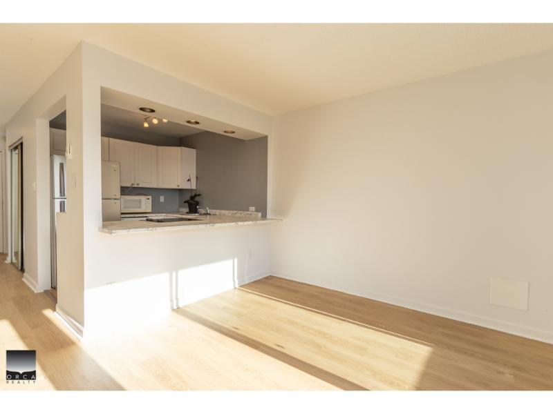 Bright open-concept living area with modern kitchen in a Vancouver-area home, featuring hardwood flooring, white cabinetry, and natural light, ideal for comfortable family living.
