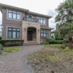 Elegant two-story house with landscaped front yard, palm tree, and classic street lamp, offering prime real estate opportunities in Vancouver area.