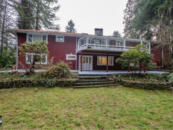 Cozy red house with a spacious backyard, surrounded by trees, perfect for family living and outdoor activities. Beautifully maintained garden with steps leading to the entrance.