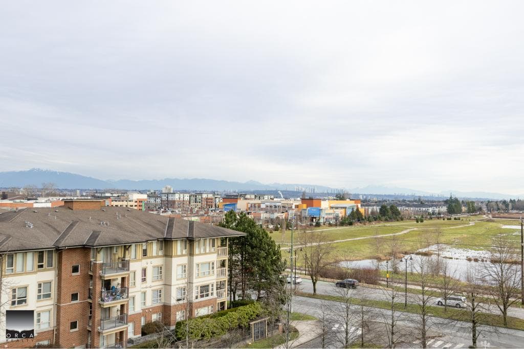 Vancouver cityscape with residential buildings, green spaces, and mountains in the background, showcasing Orca Realty Inc. real estate offerings in a scenic urban environment.