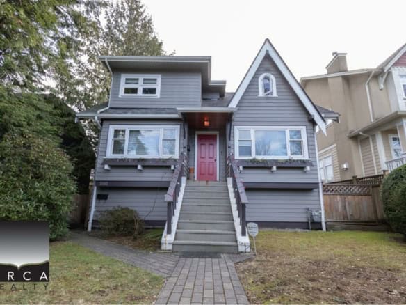 Charming grey vintage house with red door, surrounded by lush greenery, available through Orca Realty Inc., your trusted real estate expert in British Columbia.