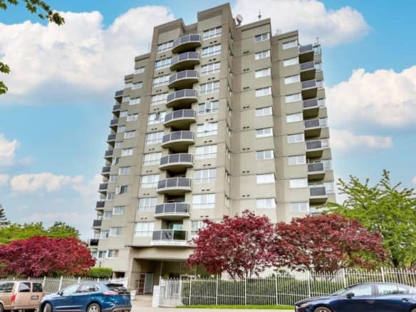 Modern multi-story apartment building with balconies, Vancouver cityscape, surrounded by vibrant red trees and parked cars, showcasing premium real estate at Orca Realty Inc.