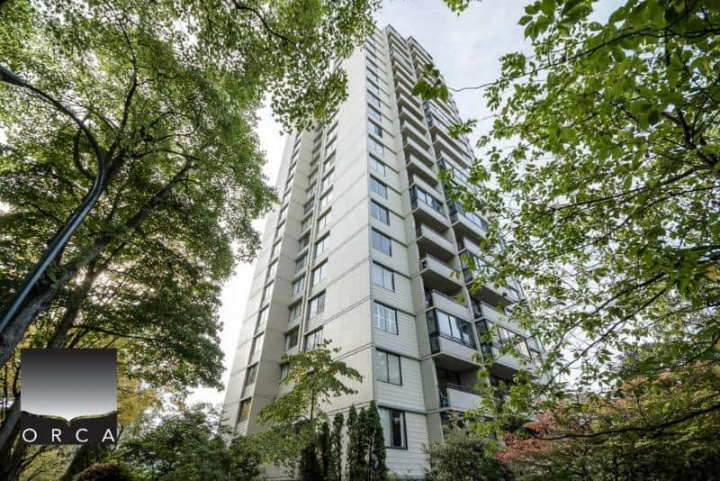 Modern high-rise condominium building surrounded by lush greenery in Vancouver, BC. Perfect for real estate investment, rental income, or upgrading to a luxury apartment. Expert agents at Orca Realty Inc. guide you.