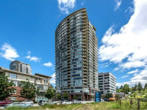 Modern high-rise condominium building in downtown Vancouver, British Columbia, with glass exterior and surrounding lush greenery.