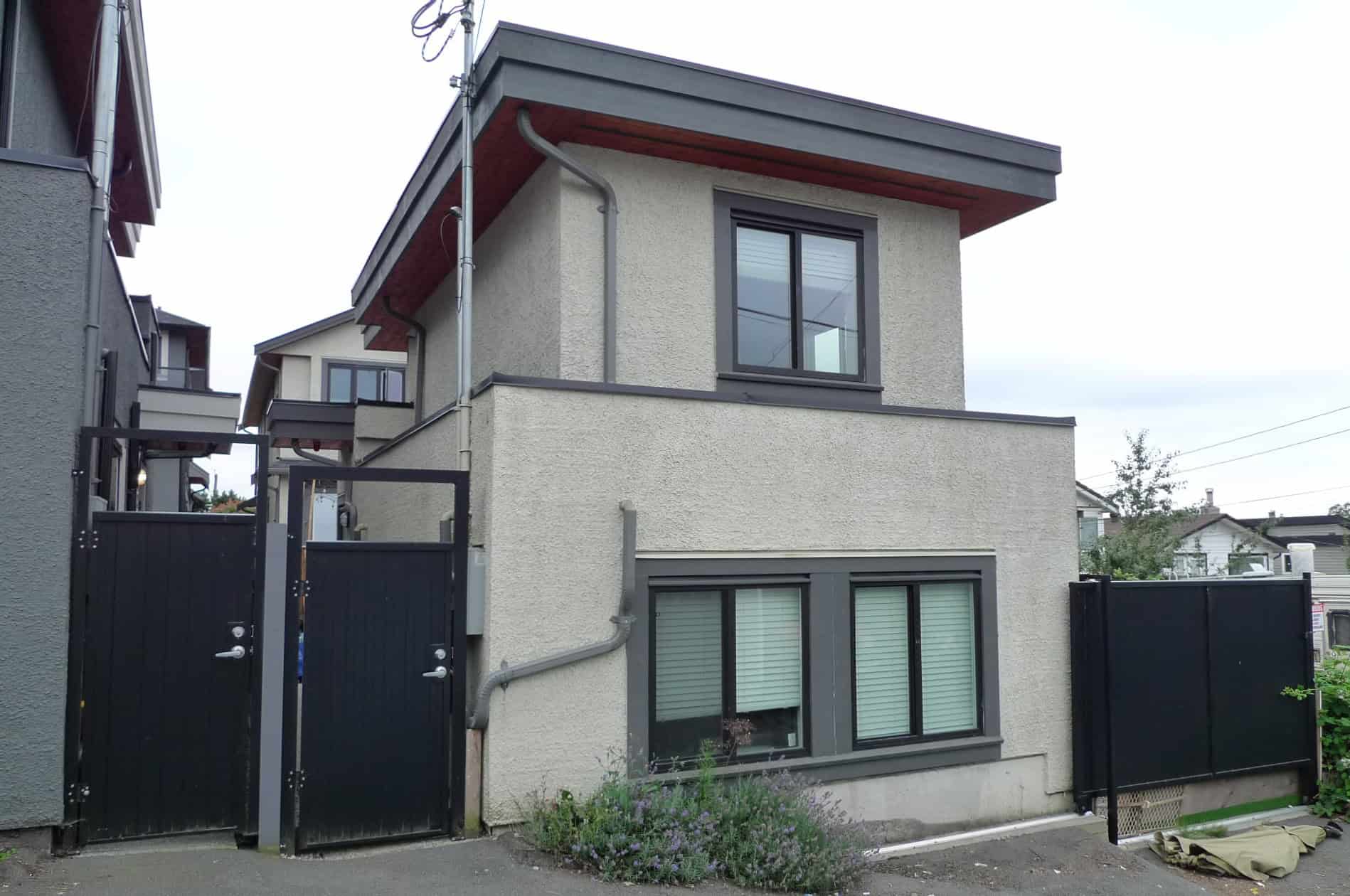 01 Contemporary two-storey residential building with modern grey window frames and a flat roof, located in a peaceful neighbourhood, showcasing Vancouver-style architecture.