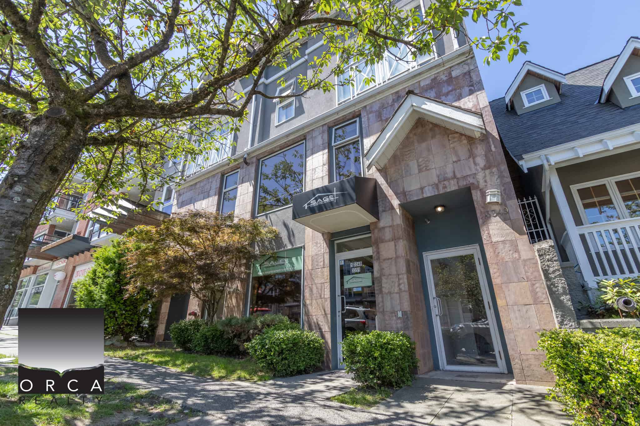 Modern commercial building with large windows, landscaped front yard, and tree in Vancouver, BC. Perfect for real estate offices or small businesses seeking prime location in a vibrant neighbourhood.
