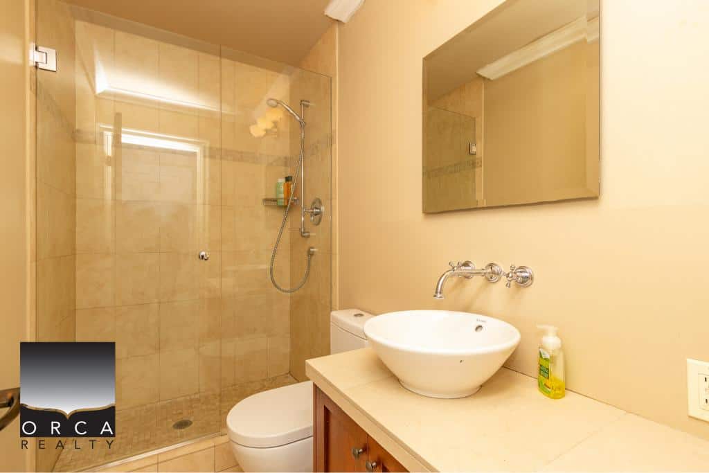Modern beige bathroom with glass-enclosed shower, vessel sink, and contemporary fixtures, perfect for Vancouver Island home or condo living.