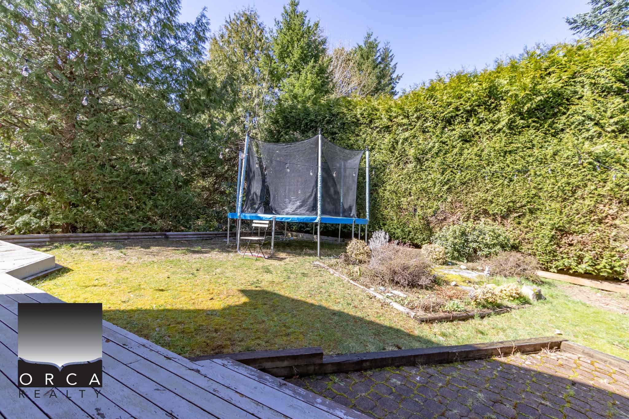 Bright backyard with a trampoline, lush greenery, and landscaped garden beds, perfect for outdoor family activities and relaxation in Vancouver.