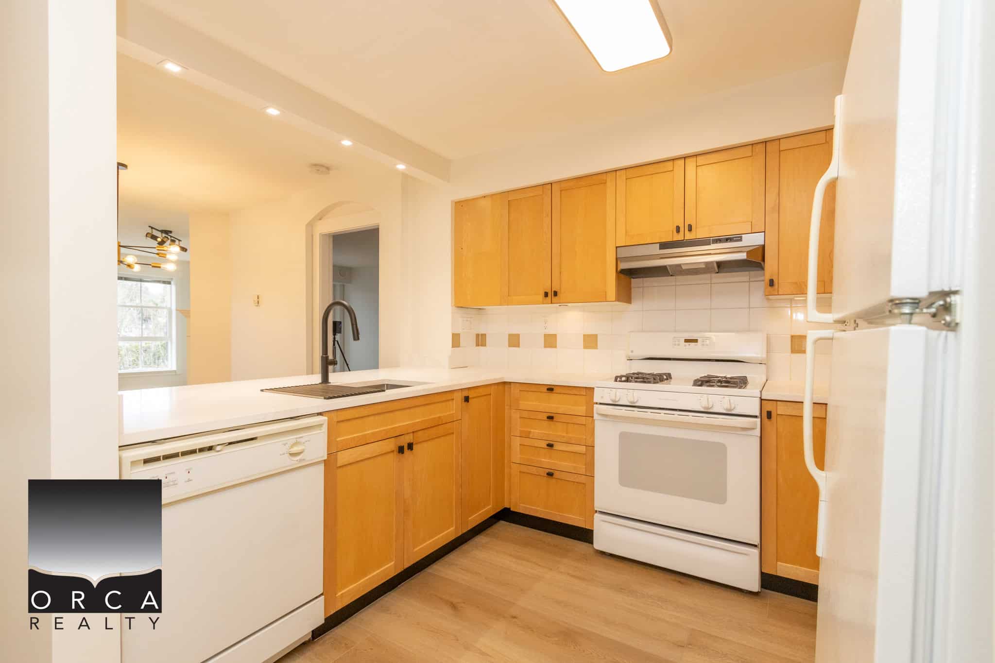 Bright kitchen with wooden cabinets, white appliances, and a modern design, ideal for Vancouver Island real estate listings by Orca Realty Inc.