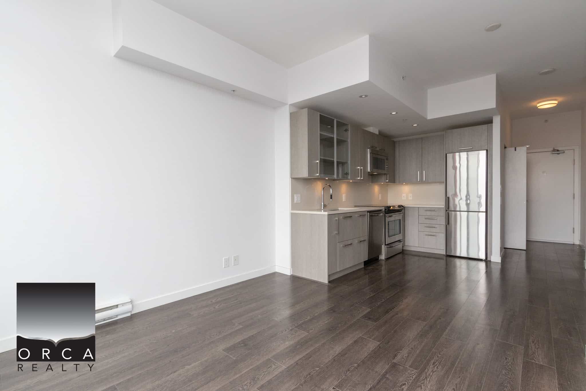Modern open-plan kitchen with stainless steel appliances in a contemporary condo unit in Vancouver. Perfect for buyers seeking sleek, stylish, and functional living space.