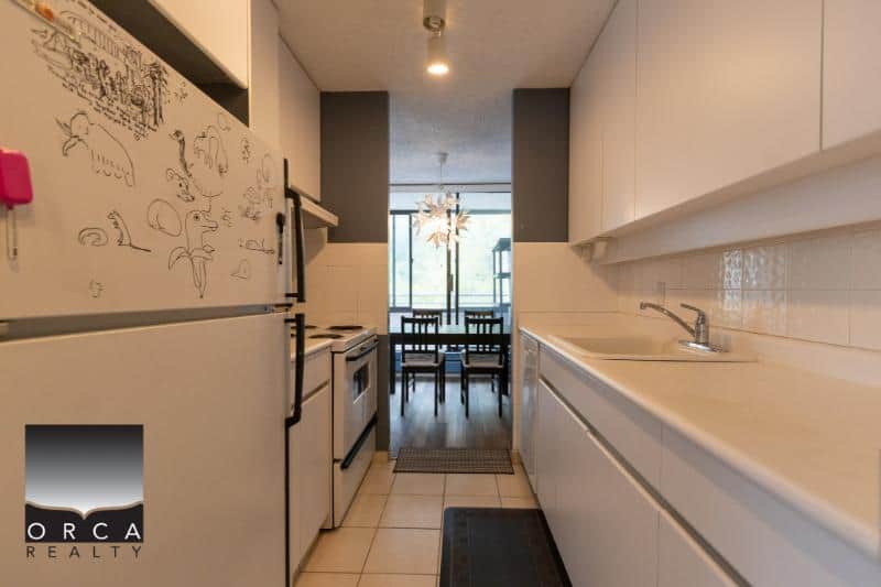 Spacious modern kitchen with white cabinets, stainless steel appliances, and a bright dining area with large windows. Perfect for comfortable living in a Vancouver area home.