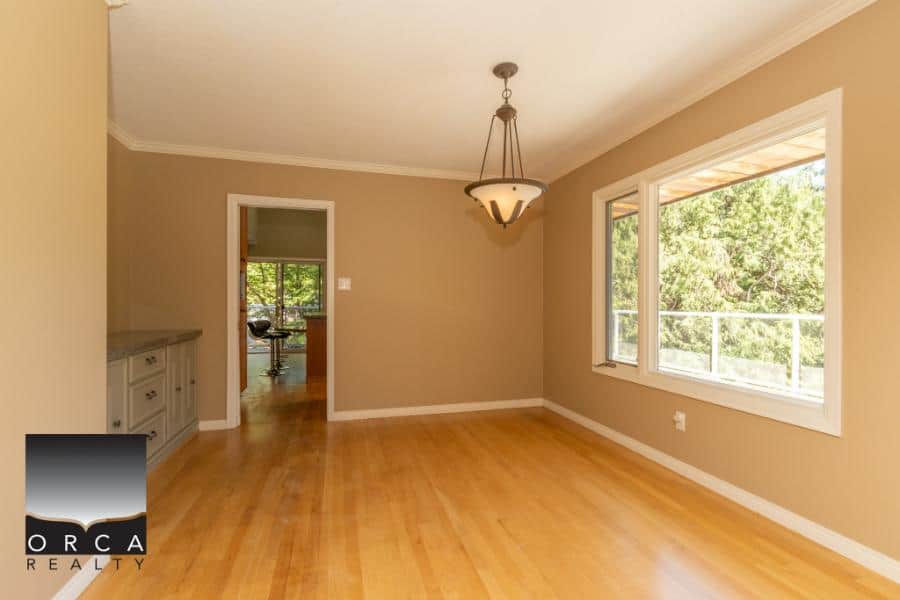 Bright and spacious living room with hardwood floors, large windows overlooking greenery, and neutral wall colours, ideal for real estate listings in Vancouver.