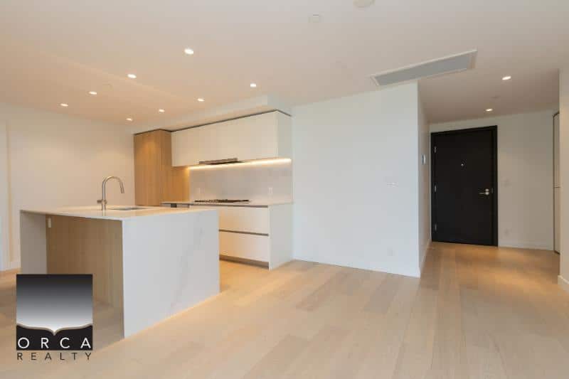 Modern open-concept kitchen with white cabinetry and a sleek island in a contemporary condo in Vancouver. Perfect for stylish living and entertaining.