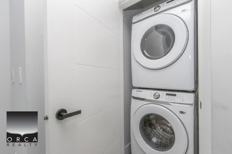 Stacked washer and dryer in a compact laundry closet, modern home appliance setup for efficient laundry at Orca Realty Inc.