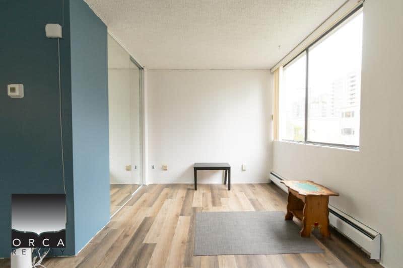 Bright, airy residential apartment with large window, minimalist decor, hardwood floors, and natural light, perfect for comfortable living.