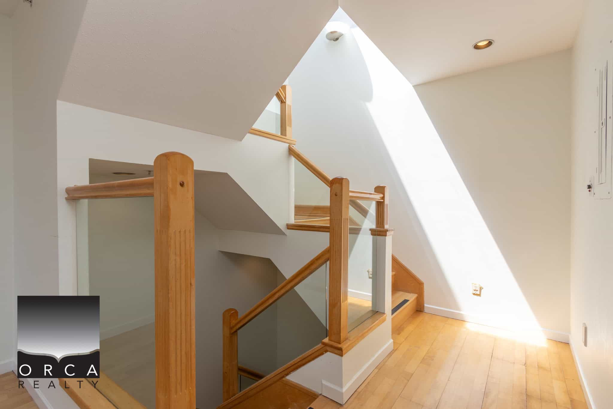 Bright interior staircase with natural wood accents and skylight for Vancouver real estate homes.