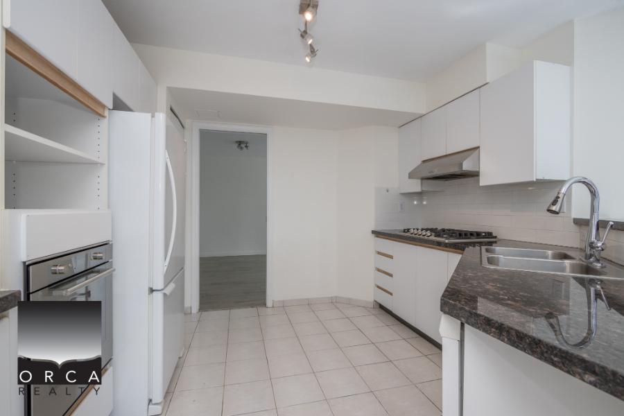 Bright modern kitchen with white cabinetry, stainless steel appliances, and granite countertops, perfect for Vancouver real estate buyers.