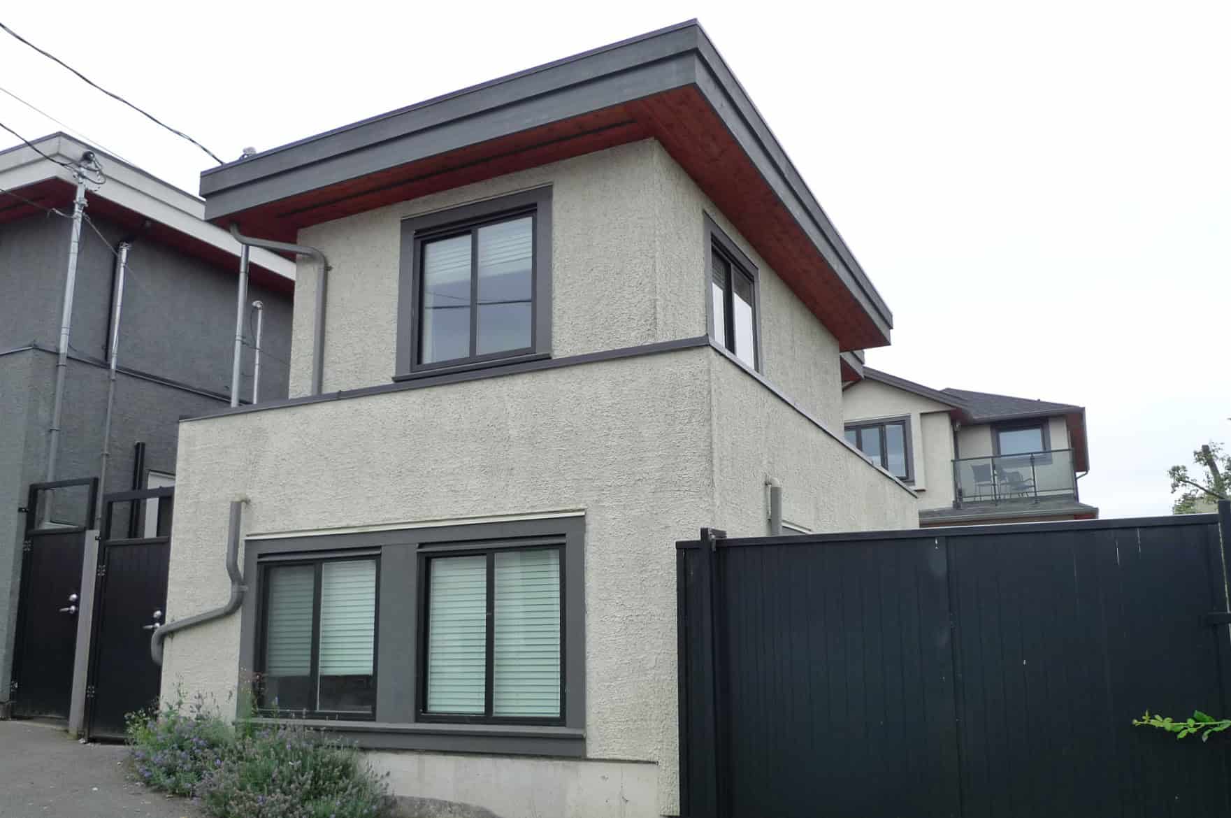 15 Modern three-storey residential home with stucco exterior, large windows, and balcony, located in a desirable neighbourhood, ideal for families or investors.