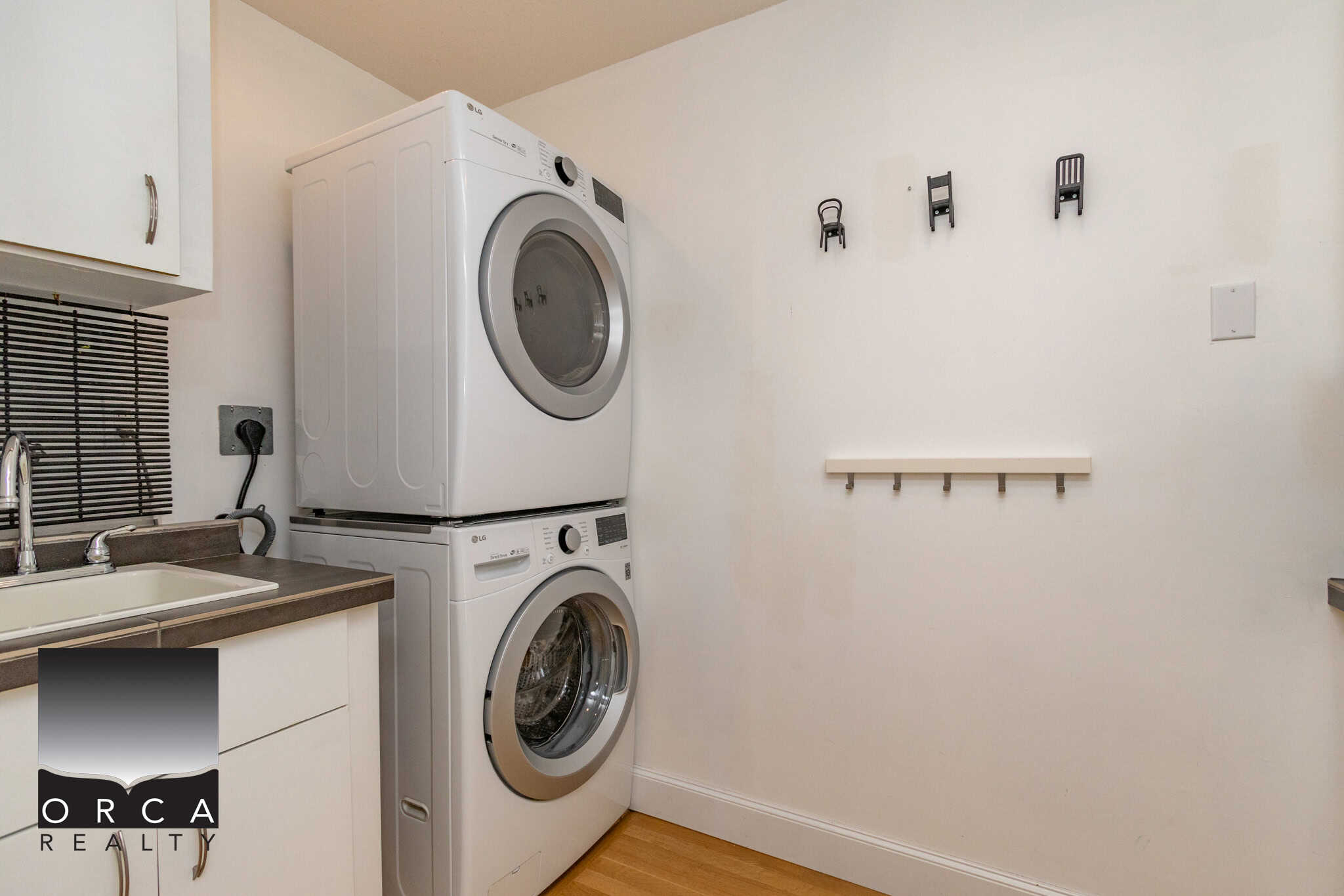Modern laundry room with stacked LG washer and dryer, ample cabinet storage, and a utility sink, perfect for Vancouver area homes.