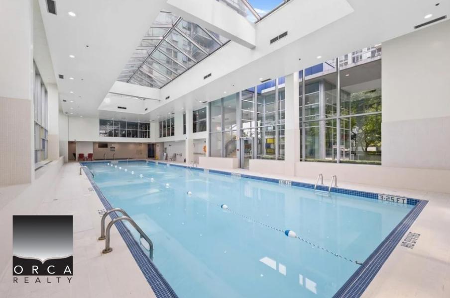 Modern indoor swimming pool at Orca Realty Inc. offering luxury amenities and indoor comfort, ideal for relaxation and fitness in a prime real estate location.