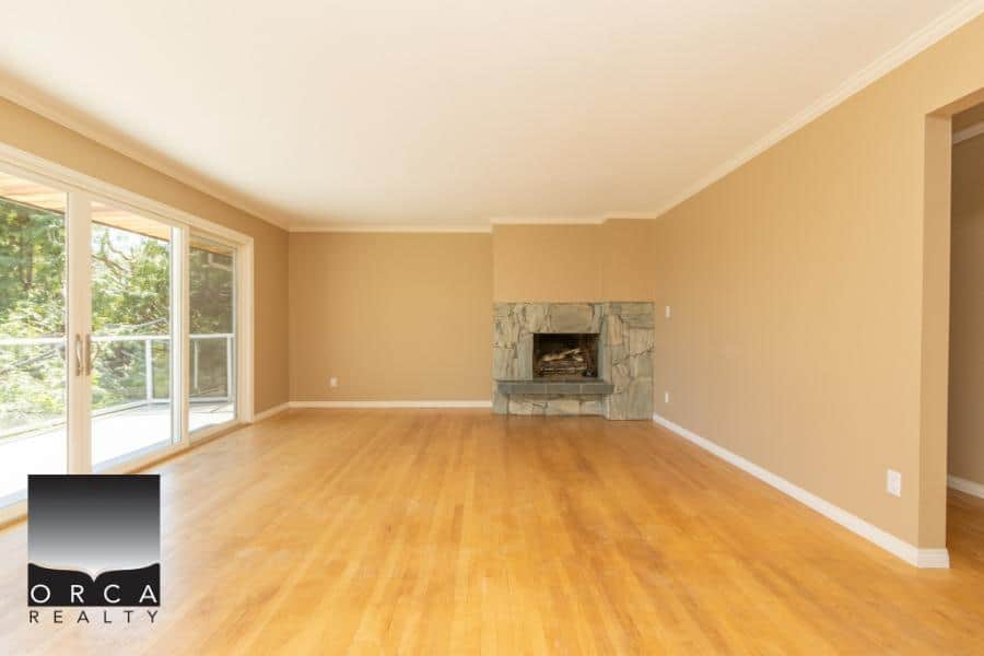 Bright living room with large sliding glass doors, hardwood flooring, and a cozy fireplace, ideal for homebuyers seeking a spacious and inviting Ontario property.